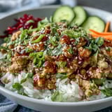 Crisp red cabbage, scallions, and sesame seeds add texture, while a lime wedge brightens the bowl.