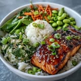 Healthy Asian-inspired salmon bowl featuring flaky soy-ginger glazed salmon atop fluffy rice, crisp vegetables, and a sprinkle of sesame seeds.  