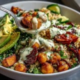 Wholesome Buddha Bowl featuring fluffy quinoa, golden roasted sweet potatoes, crunchy chickpeas, and crisp vegetables topped with rich garlic tahini sauce.  