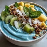 Blue spirulina smoothie bowl overflowing with colorful tropical fruits.