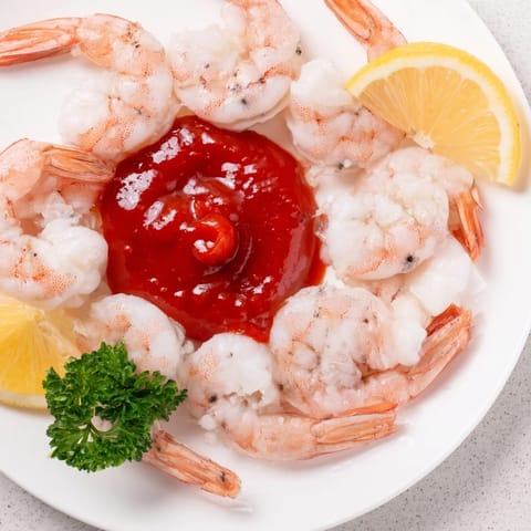 Beautiful platter of classic shrimp cocktail, showing perfectly cooked pink shrimp ready to eat.