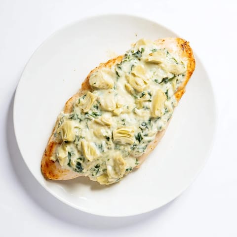 A close-up of spinach artichoke chicken bake served alongside fluffy quinoa and a crisp green salad.  