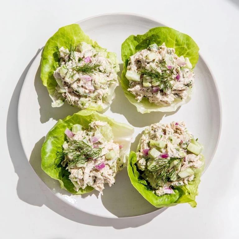 Savory dill pickle chicken salad served in butter lettuce cups, garnished with fresh herbs for a refreshing low carb meal.