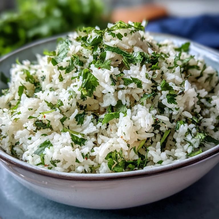 Steaming bowl of fluffy Cilantro Lime Rice with chopped cilantro and lime wedges, perfect for a Mexican-inspired meal.