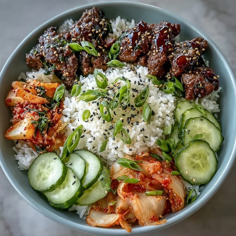 Spicy Korean Beef Bowl served with steamed rice, tangy kimchi, and colorful quick-pickled radish and carrot for a balanced, bold flavor.  