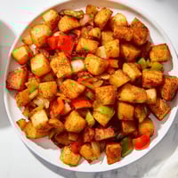 Golden-brown home fries with crispy edges are served alongside breakfast, a classic American side.