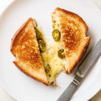 Golden-brown sourdough slices, grilled to crispy perfection, oozing with melted pepper jack cheese and dotted with tangy pickled jalapeños.