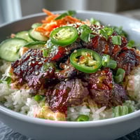 Sizzling sesame-ginger beef sits atop fluffy rice in this vibrant Korean Beef Power Bowl, garnished with pickled carrots and cucumber.