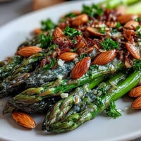 Bright asparagus spears glisten in lemon butter sauce, topped with golden toasted almonds for a vibrant spring side dish.